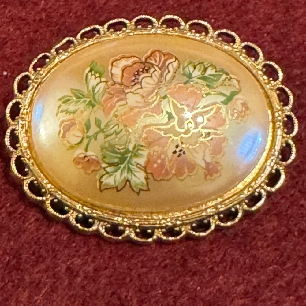 Vintage hand painted floral celluloid set in gold tone filigree frame brooch